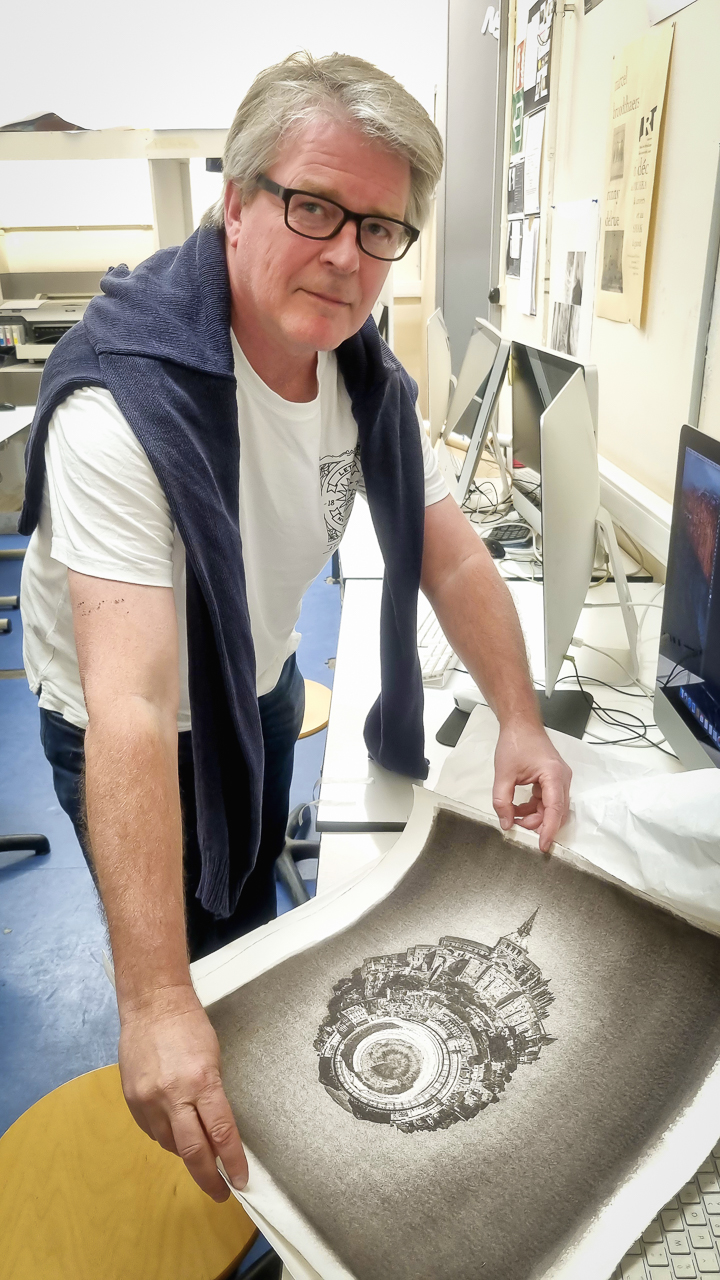 Frédéric Materne dans son atelier, penché sur le tirage pigmentaire d’une Planète Imaginaire de Paul Marnef