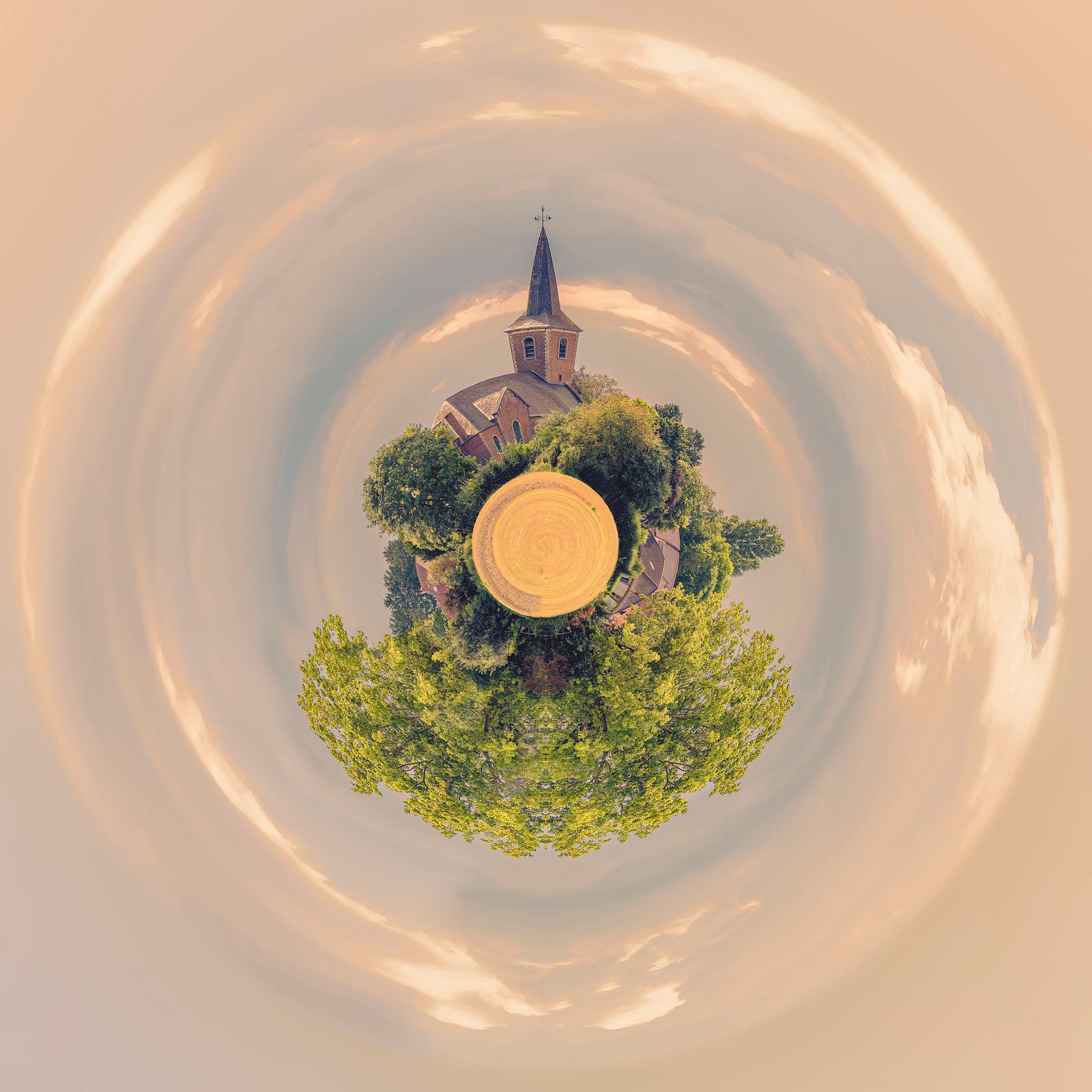 The Village, with the church and trees forming a mini-planet beneath a golden sky, photograph by Paul Marnef