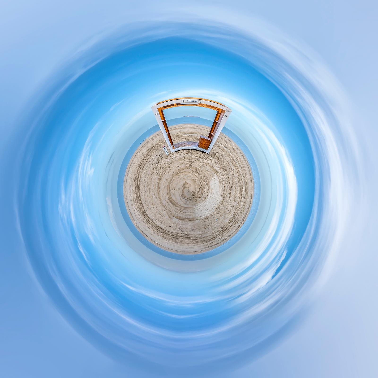 Pauline, une cabine de plage sur une mini-planète de sable sous un ciel bleu, photographie de Paul Marnef