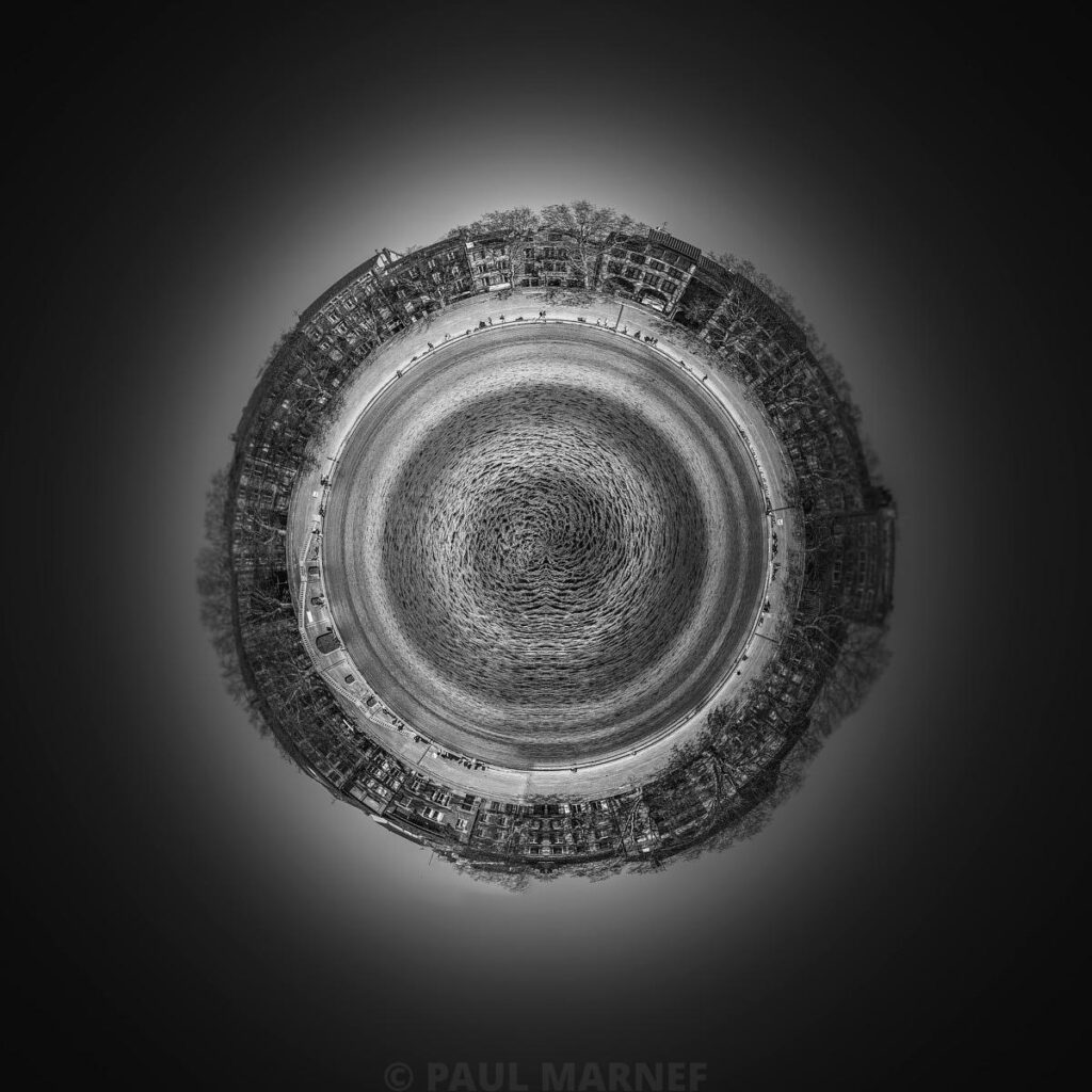 Photo noir et blanc montrant la Garonne en spirale entourée de maisons bordant un quai, dans une composition circulaire sur fond clair.
