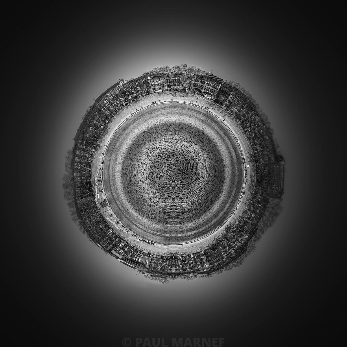 Photo noir et blanc montrant la Garonne en spirale entourée de maisons bordant un quai, dans une composition circulaire sur fond clair.