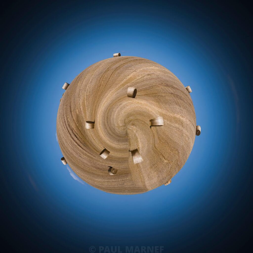 Sphère en paille aux brins entrelacés en spirale, émergent de petits rouleaux de foin sur un fond de ciel bleu.