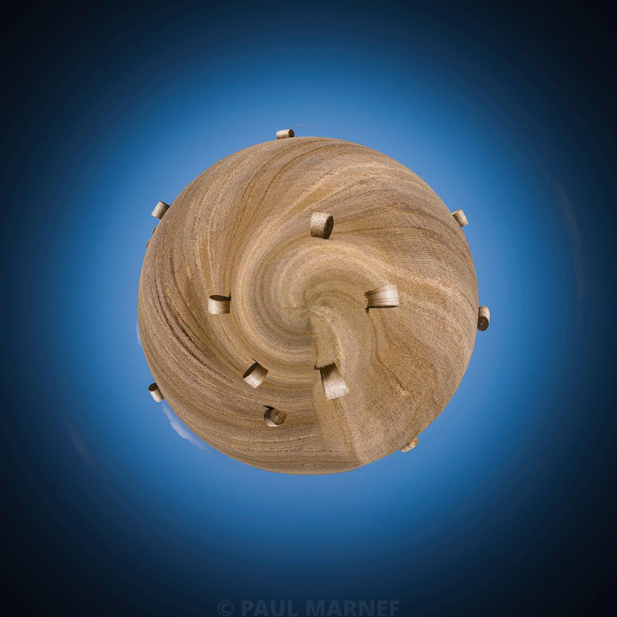 Sphère en paille aux brins entrelacés en spirale, émergent de petits rouleaux de foin sur un fond de ciel bleu.