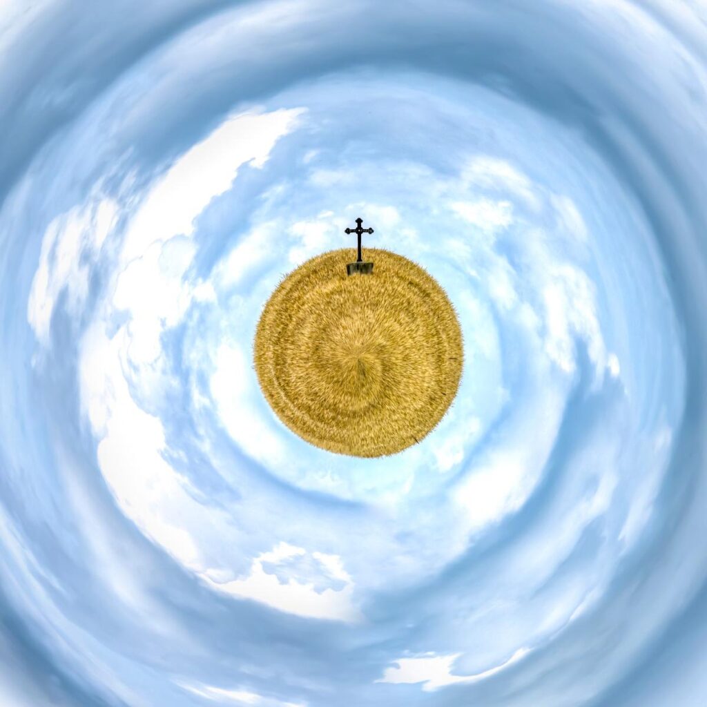 Un ciel bleu et des nuages en spirale entourent une boule d'herbe jaune surmontée d'une croix sombre.