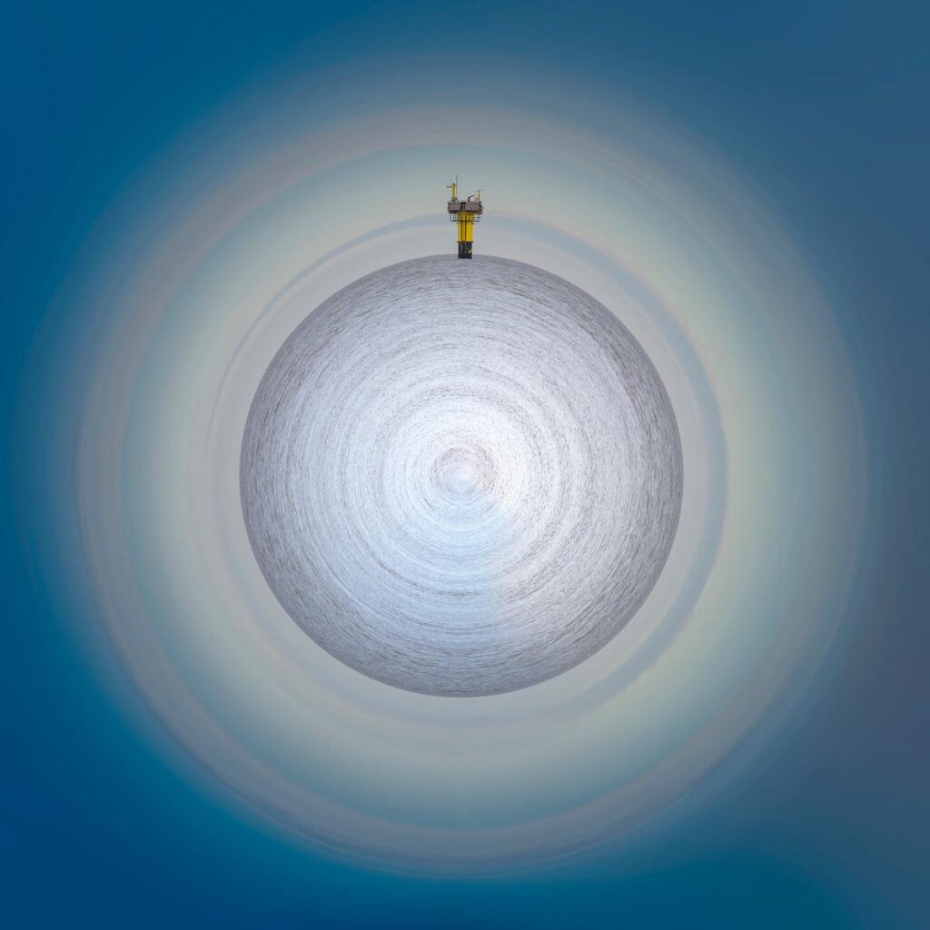 A yellow technical structure crowns the tip of a grey-textured globe, set against a gradient of pale blue sky.