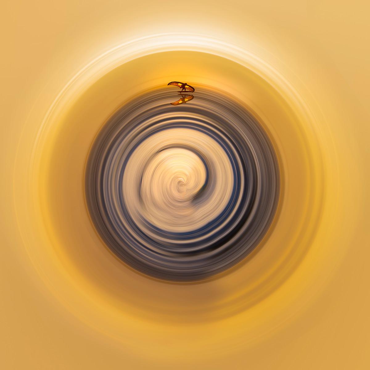 Spirales concentriques bleutées et blanches sur fond jaune lumineux, avec une silhouette floue au sommet de la structure.