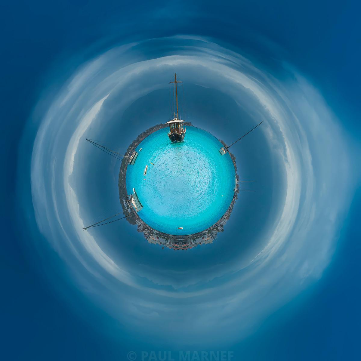 Une bulle turquoise cerclée de nuages et un mât flottent dans un océan de brume bleue.