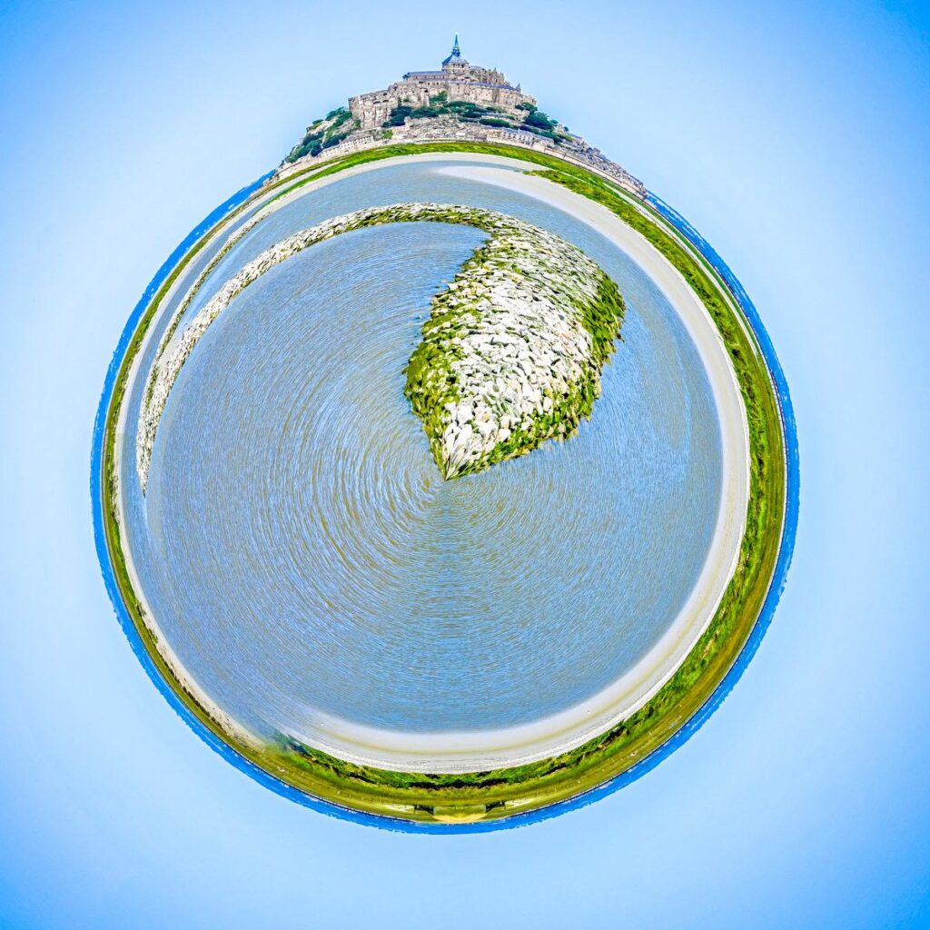 Forteresse perchée au sommet d'une île rocheuse entourée d'eau, de plages et de ceinture verdoyante sous le ciel.