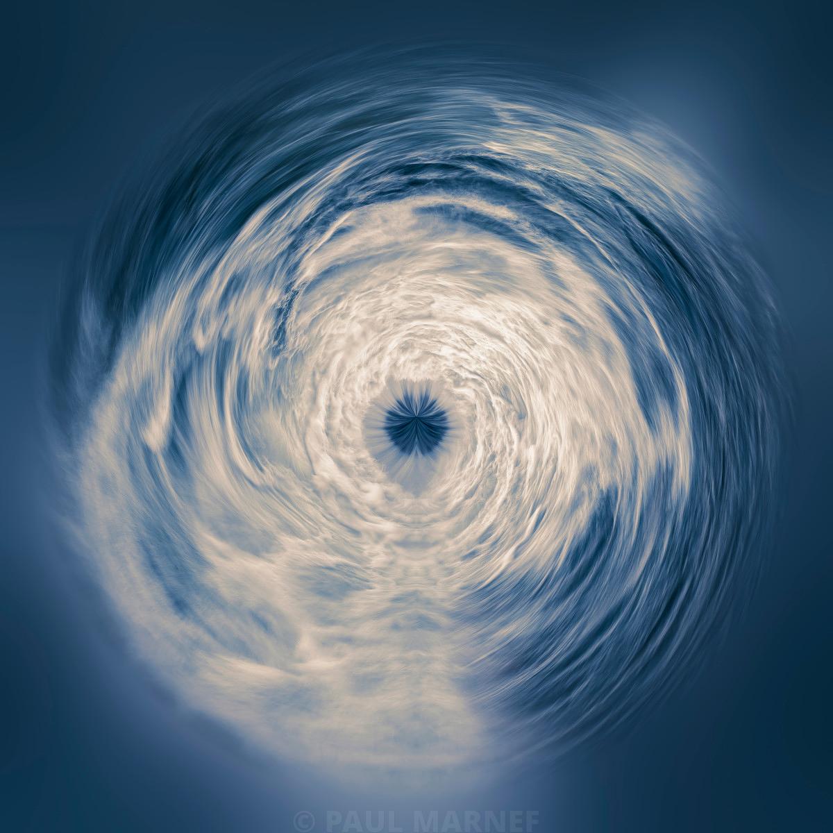 Nébuleuse tourbillonnante de nuages blancs et gris foncé en forme de spirale sur fond bleu nuit.