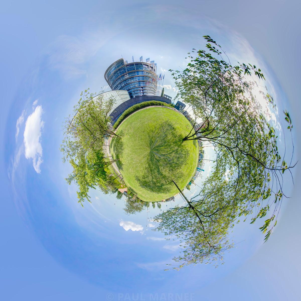Vue plénuisque montrant un bâtiment vitré courbée au centre du ciel, entouré d'une pelouse verte et de branches dénudées.