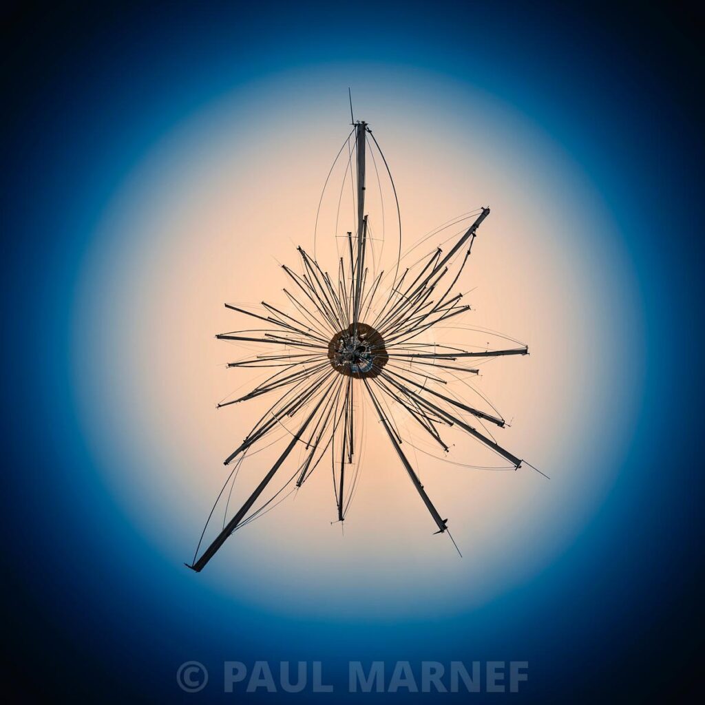 A radiant, star-studded metallic silhouette in the background stands out against a disc of warm light glowing against a deep blue sky.