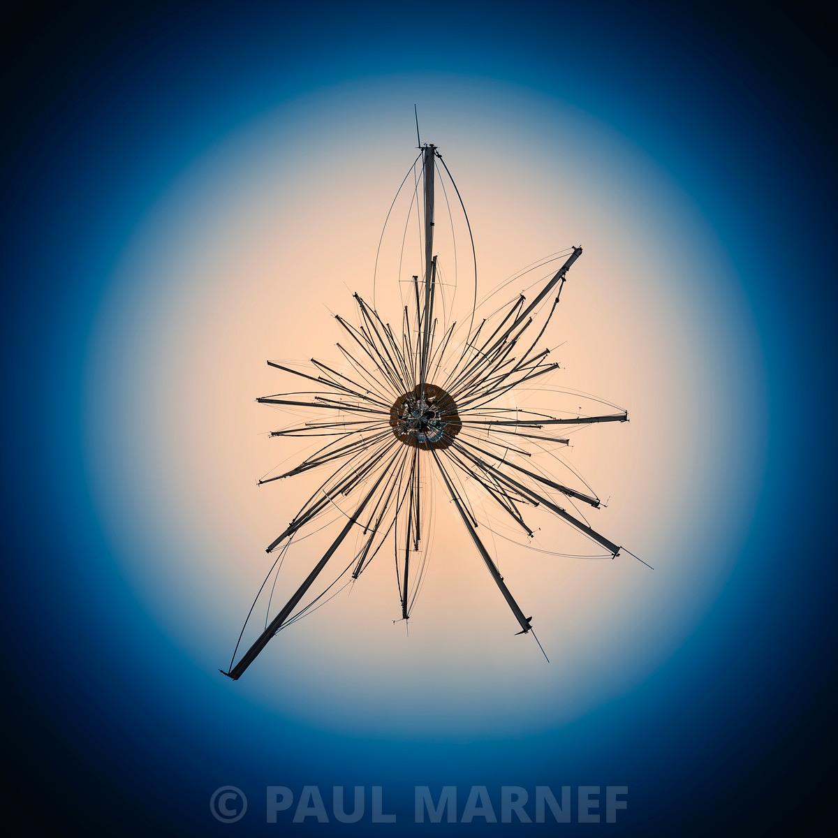 Une silhouette métallique rayonnante et étoilée en arrière-plan se détache sur un disque de lumière chaude s'auréolant dans un ciel bleu profond.