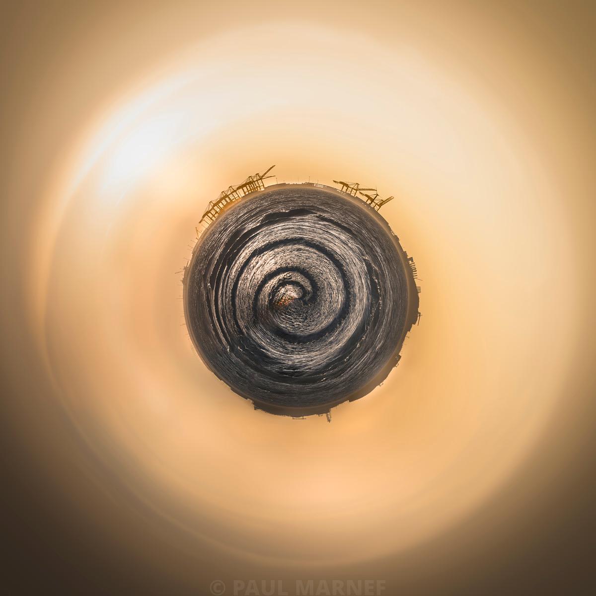 Un vortex gris concentrique est entouré d'un halo lumineux ambré où des grues portuaires sont visibles en silhouette.