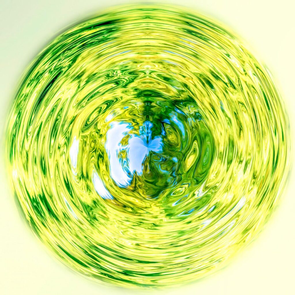 A sphere shimmering with swirling greens and yellows, at the centre of which sky blue emerges against a white background.