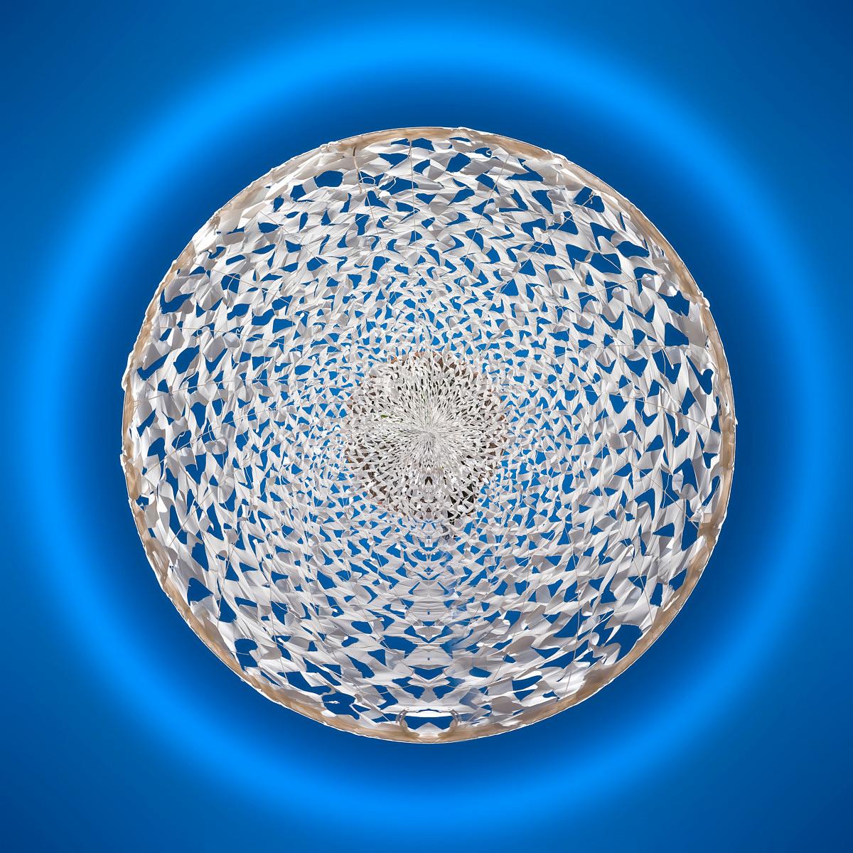 Structure textile croulante de blanc d'œuf torsadé en spirale tridimensionnelle flottant dans une lumière bleue circulaire.