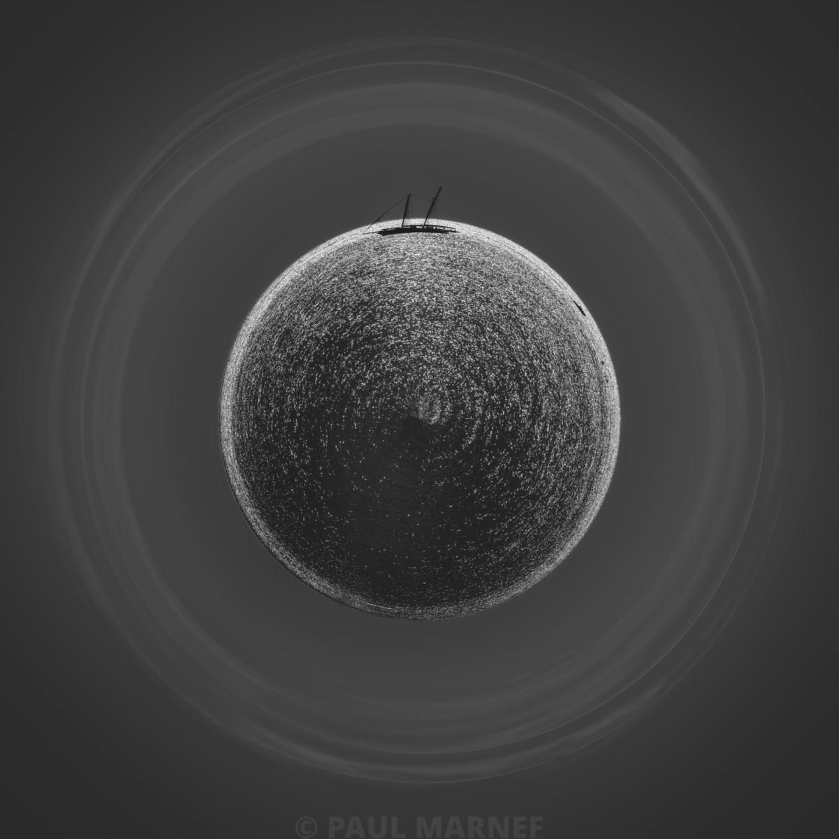Une scène monochrome où des gouttelettes d'eau forment une sphère scintillante entourée de cercles concentriques, sur un fond sombre.