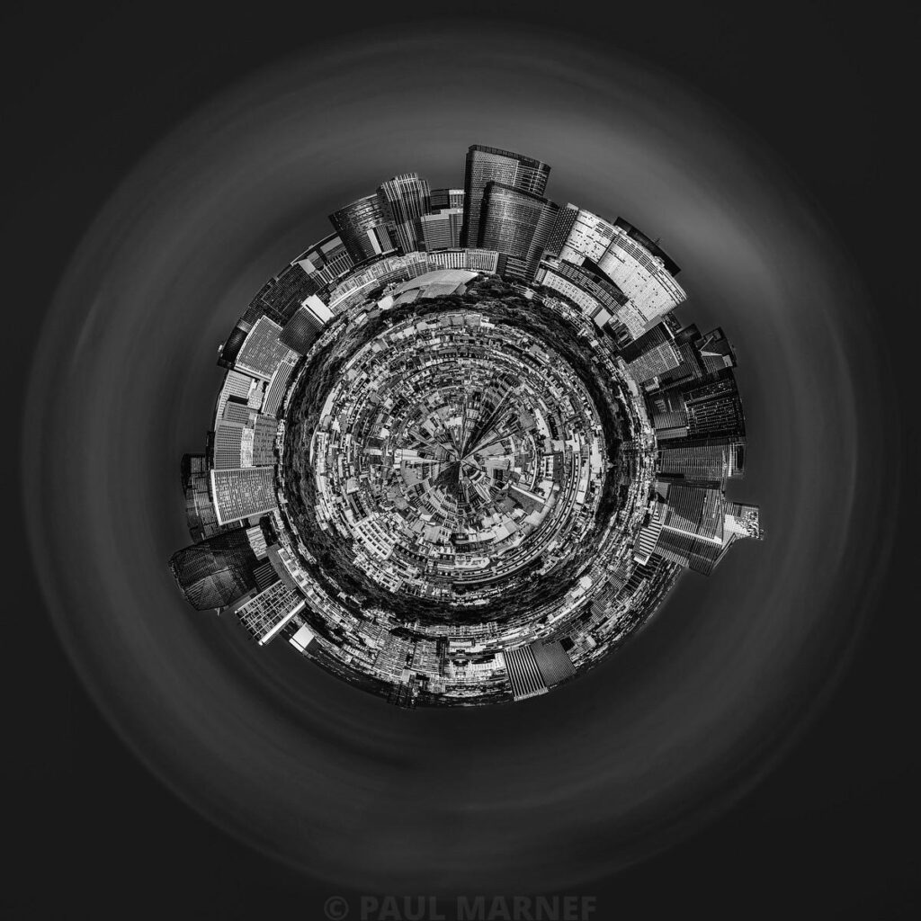 A multi-angle black-and-white view of a conurbation curved around a central, sphere-shaped axis, with skyscrapers encircling a vast urban landscape.