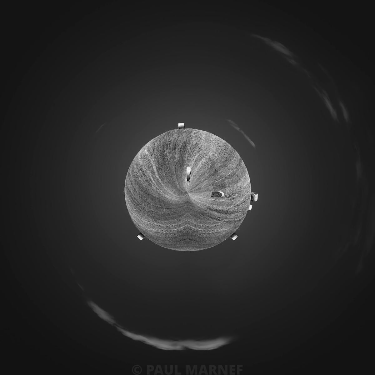 Un disque gris strié entaillé de deux vides flotte sur un fond sombre, encadré de quatre petites formes lumineuses et de flous circulaires.