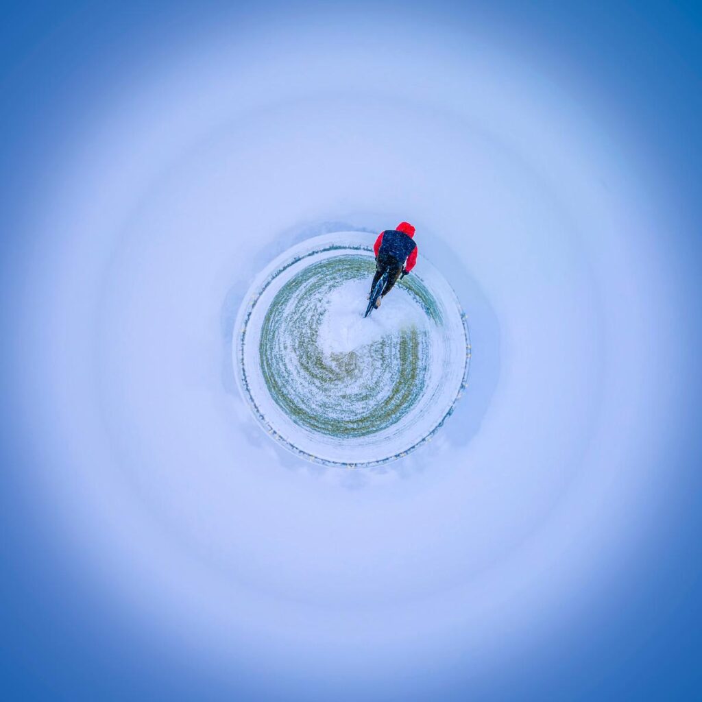 Vue plongeante sur un cycliste en combinaison rouge avançant en plein ciel bleu vaporeux.