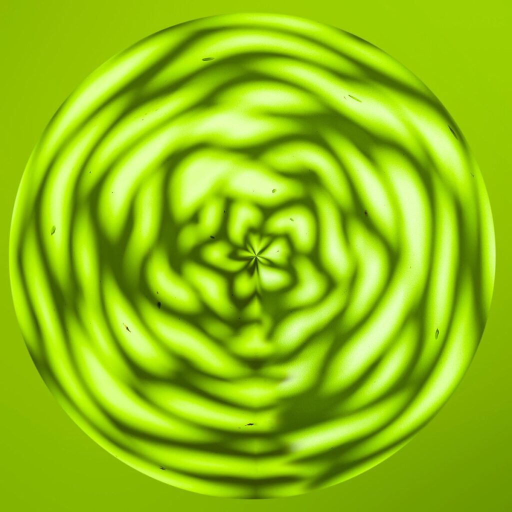 Spiral shapes with shimmering undulations create a yellowish-green circular pattern against a bright green background.