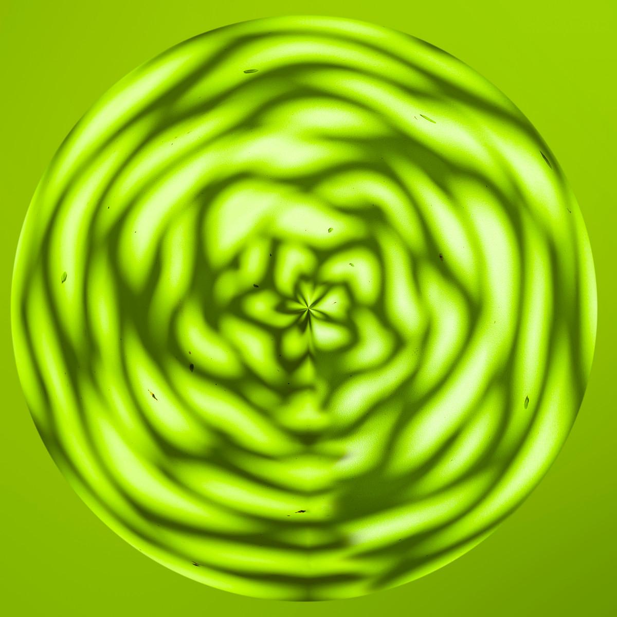 Des formes spirales aux ondulations lumineuses créent un motif circulaire vert jauni sur un fond vert vif.