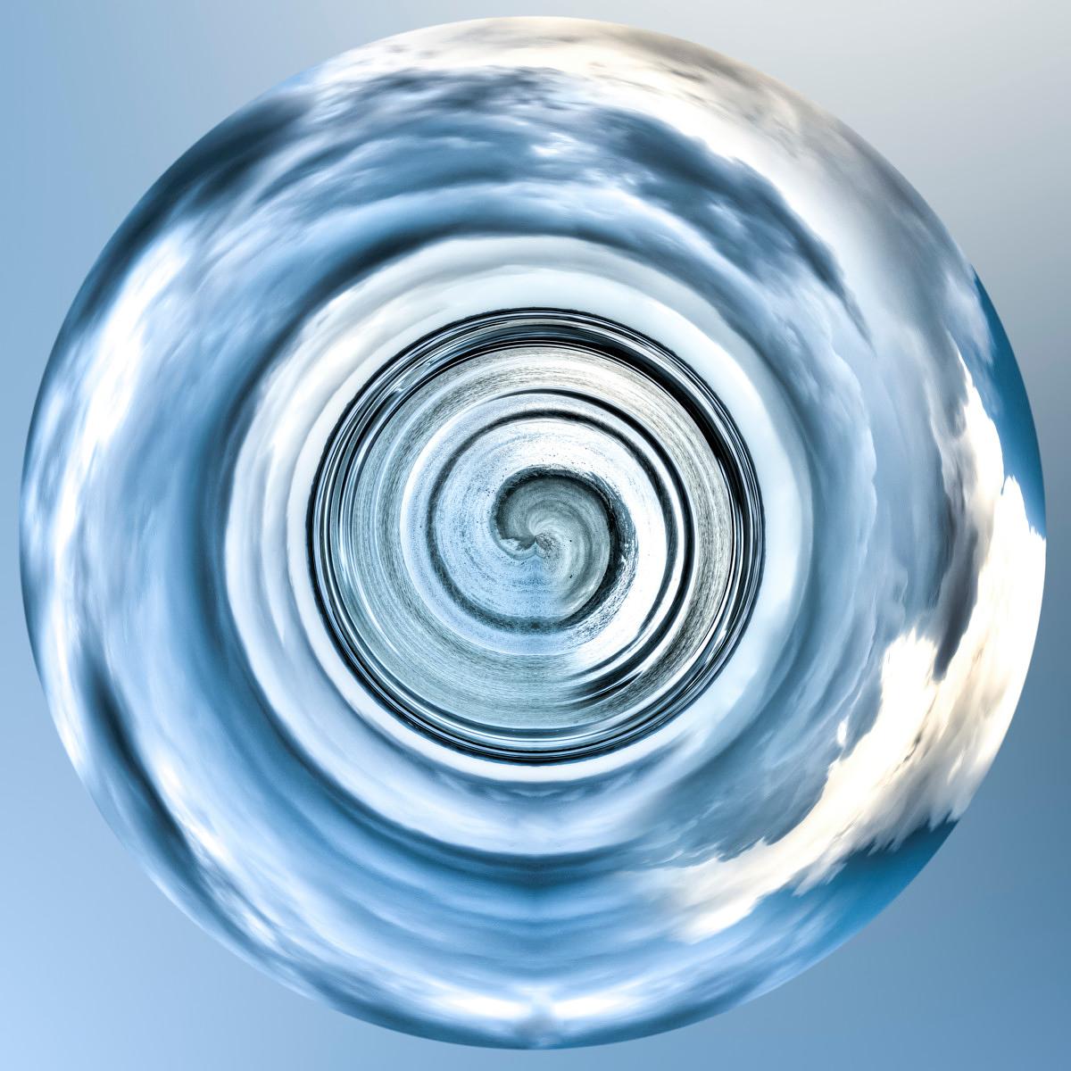 Une sphère de verre contient une répétition concentrique du ciel bleu et des nuages blancs en spirale.