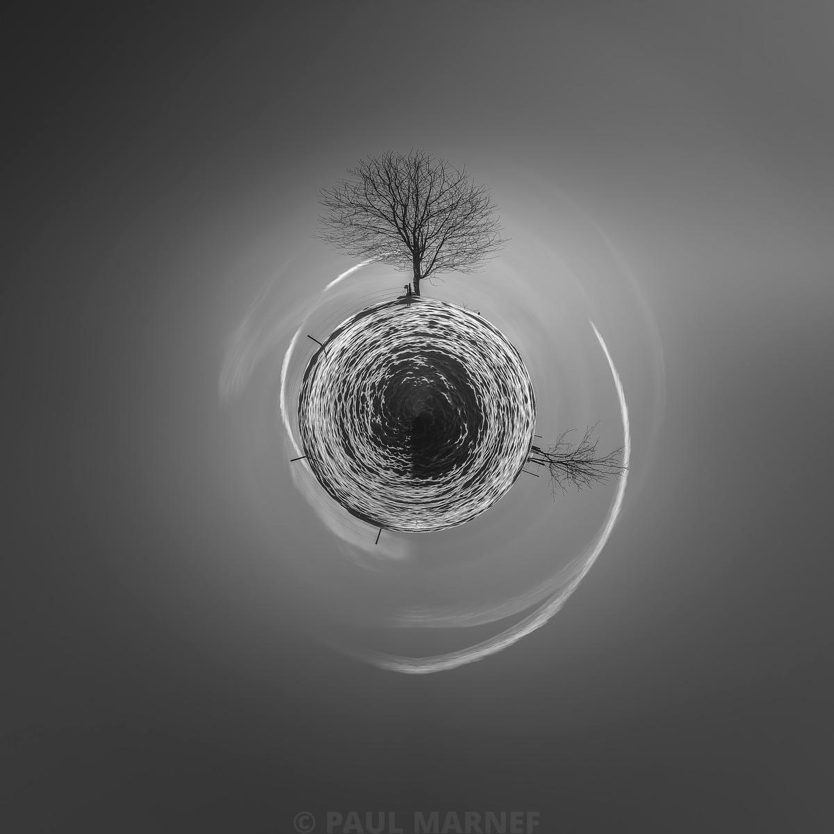 Arbre dénudé sur une pelouse relevée et un disque circulaire en spirale au centre d'un ciel gris tourbillonnant.