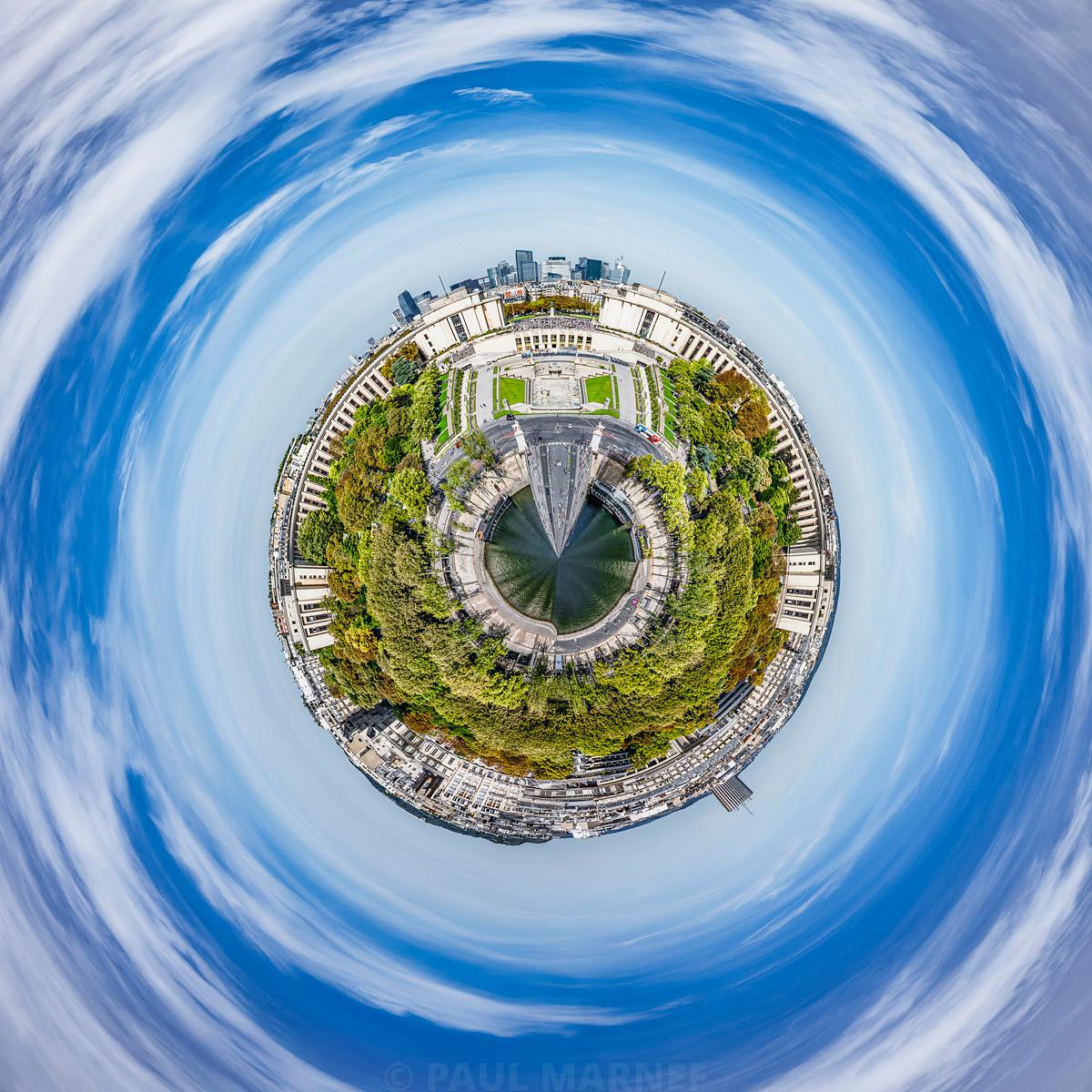 Vue en 360 degrés de Paris plongée dans une distorsion en toute-petite-planète sous un ciel azur strié de nuages blancs.