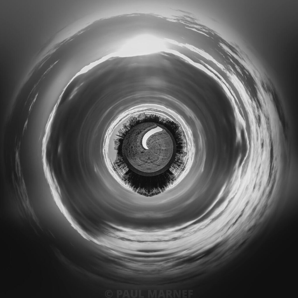 Brouillard nuageux en spirale large encadrant un œil sombre au centre d'un entonnoir atmosphérique.