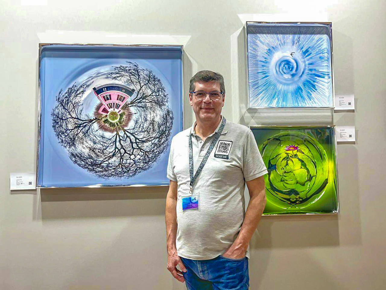 Paul Marnef devant trois œuvres de sa série Planètes Imaginaires, exposées au salon Art Capital au Grand Palais à Paris.