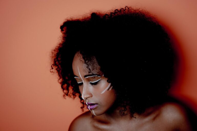 Portrait artistique d'une femme avec des peintures faciales blanches, capturé par Paul Marnef, photographe portraitiste à Bruxelles, mettant en valeur son expression contemplative et sa beauté naturelle.