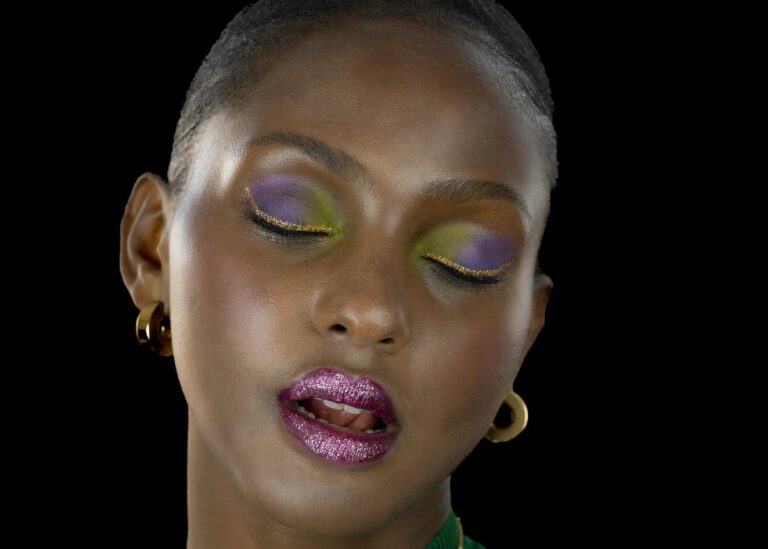 Portrait artistique d'une femme avec un maquillage vibrant aux couleurs vives, capturé par Paul Marnef, photographe portraitiste à Bruxelles. Les yeux fermés du modèle expriment une émotion subtile, ajoutant une touche de glamour.