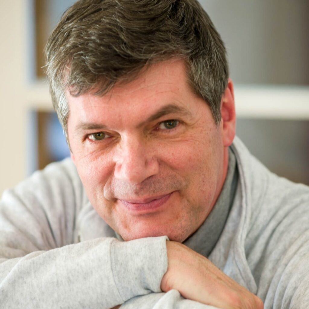 Portrait of Paul Marnef, his chin resting on his arms, wearing a light grey sweatshirt